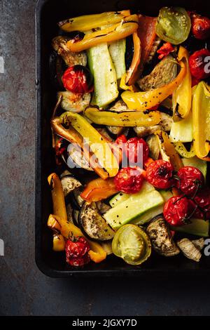 Gebratenes, geschnittenes Gemüse auf einem Backblech. Im Ofen gebackene Tomaten, Auberginen, Zucchini, Paprika. Stockfoto