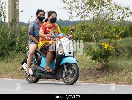 SAMUT PRAKAN, THAILAND, MAI 05 2022, zwei Frauen fahren auf dem Motorrad auf der Landstraße Stockfoto