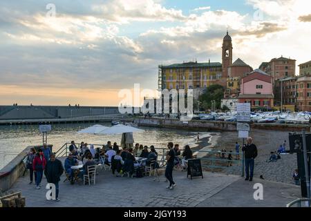 Blick auf das alte Fischerdorf mit Menschen am Wasser cafè und den kleinen Hafen im Frühling bei Sonnenuntergang, Nervi, Genua, Ligurien, Italien Stockfoto