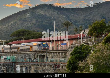 Ein Zug im Bahnhof Genova Nervi, der sich bei Sonnenuntergang über dem Uferweg Anita Garibaldi Promenade befindet, Nervi, Genua, Ligurien, Italien Stockfoto
