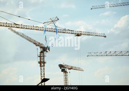 Fliegender Drachen aus Kunststoff und Korbholz mit einem Hintergrund einer Baustelle von Neubauten, Kränen und Hektar luxuriöser Immobilien resid Stockfoto