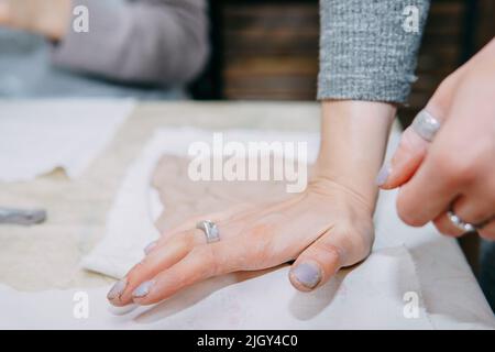 Weibliche Hände kneten Ton. Herstellung von keramischen Produkten in der Meisterklasse auf Keramik. Nahaufnahme. Stockfoto