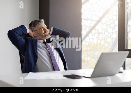Porträt von glücklich reifen männlichen Unternehmer entspannen am Arbeitsplatz im Büro Stockfoto