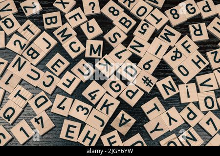 Holzfliesen mit lateinischen Buchstaben und Schriftzeichen, schwarzer Hintergrund Stockfoto