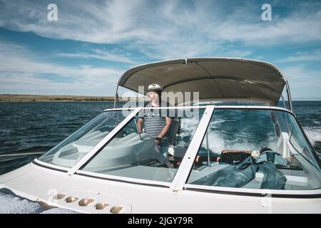 Der Kapitän der Yacht am Steuer steuert das Boot auf dem Wasser. Stockfoto