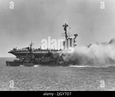 Der Zerstörer der US-Marine USS Rupertus (DD-851) unterstützt den Flugzeugträger USS Forrestal (CVA-59) beim Kampf gegen wütende Decksbrände und Explosionen im Golf von Tonkin, 29. Juli 1967. Der Kapitän der Rupertus maneouvered sein Schiff innerhalb von 6 Metern von der brennenden Träger, in dem Konteradmiral Harvey P. Lanham, Commander Carrier Division 2, nannte einen Akt der "agnificent Seemanship". Stockfoto