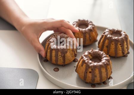 Childs Hand taken Beschichtung mit Schokolade Glasur lecker handgemachte Muffins Stockfoto