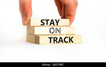 Symbol „auf Kurs bleiben“. Konzeptwörter bleiben auf Holzblöcken auf einem schönen weißen weißen Hintergrund auf Kurs. Geschäftsmann Hand. Geschäft, Motivation Stockfoto