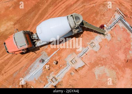 In dieser Luftaufnahme gießen Arbeiter Betonsäulen in ein neues Gebäude auf der Baustelle Stockfoto