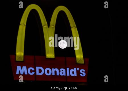 Nikosia, Zypern. 13.. Juli 2022. Am 13. Juli 2022 steigt der Vollmond über der Stadt hinter einem McDonald's-Schild, Nikosia, Zypern, auf. Der Buck Moon im Juli umkreist näher an der Erde als jeder andere Vollmond in diesem Jahr, was ihn zum größten und hellsten Supermond des Jahres 2022 macht, und er wird Buck Moon genannt, weil das Geweih der männlichen Hirsche (Böcke) zu diesem Zeitpunkt im Vollwachstumsmodus ist. (Foto von Kostas Pikoulas/Sipa USA) (Foto von Kostas Pikoulas/Sipa USA) Quelle: SIPA USA/Alamy Live News Stockfoto