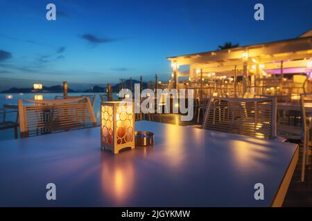 Schöne Lampe auf dem Tisch im Café an der Küste in der Nacht Stockfoto