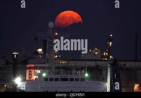 Hamburg, Deutschland. 13.. Juli 2022. Der Vollmond steigt am Abend über dem Hamburger Hafen auf. Gleichzeitig ist der Mond nahe an der Erde, weshalb er als Supermond bezeichnet wird. Kredit: Marcus Brandt/dpa/Alamy Live Nachrichten Stockfoto