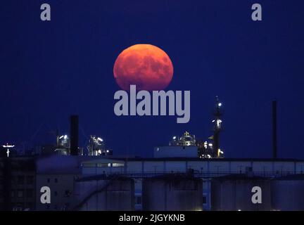 Hamburg, Deutschland. 13.. Juli 2022. Der Vollmond steigt am Abend über dem Hamburger Hafen auf. Gleichzeitig ist der Mond nahe an der Erde, weshalb er als Supermond bezeichnet wird. Kredit: Marcus Brandt/dpa/Alamy Live Nachrichten Stockfoto