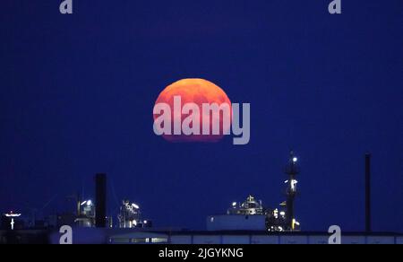 Hamburg, Deutschland. 13.. Juli 2022. Der Vollmond steigt am Abend über dem Hamburger Hafen auf. Gleichzeitig ist der Mond nahe an der Erde, weshalb er als Supermond bezeichnet wird. Kredit: Marcus Brandt/dpa/Alamy Live Nachrichten Stockfoto