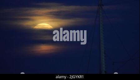 Hamburg, Deutschland. 13.. Juli 2022. Der Vollmond steigt am Abend über dem Hamburger Hafen auf. Gleichzeitig ist der Mond nahe an der Erde, weshalb er als Supermond bezeichnet wird. Kredit: Marcus Brandt/dpa/Alamy Live Nachrichten Stockfoto
