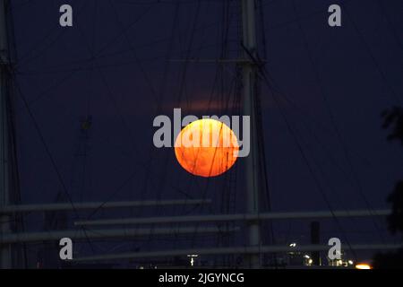 Hamburg, Deutschland. 13.. Juli 2022. Der Vollmond steigt am Abend über dem Hamburger Hafen auf. Gleichzeitig ist der Mond nahe an der Erde, weshalb er als Supermond bezeichnet wird. Kredit: Marcus Brandt/dpa/Alamy Live Nachrichten Stockfoto