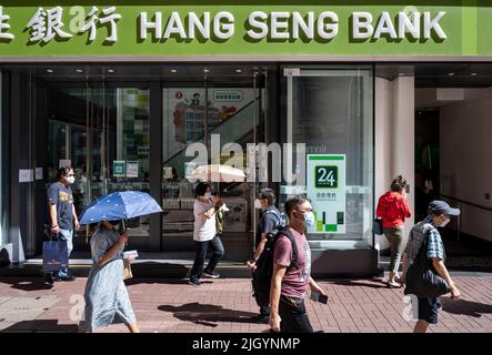 Fußgänger werden gesehen, wie sie die Straße vor der Filiale der Hang Seng Bank in Hongkong überqueren. Stockfoto