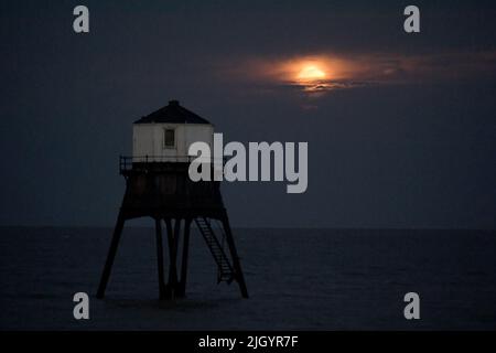 Essex, Großbritannien. 13.. Juli 2022. Dovercourt Essex UK 13.. Juli 22 der Super Buck Moon steigt hinter dem Dovercourt Lower Lighthouse in Essex auf. Der Super Buck Moon ist der zweite Supermond des Jahres und der erste Vollmond des Sommers 2022. Quelle: MARTIN DALTON/Alamy Live News Stockfoto