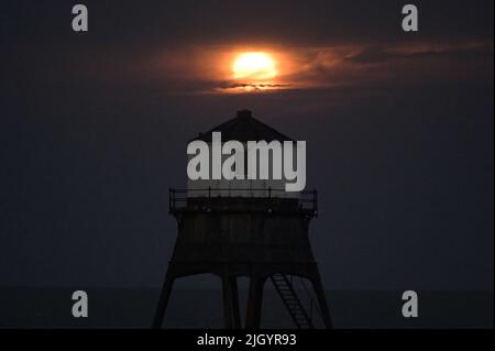 Essex, Großbritannien. 13.. Juli 2022. Dovercourt Essex UK 13.. Juli 22 der Super Buck Moon steigt hinter dem Dovercourt Lower Lighthouse in Essex auf. Der Super Buck Moon ist der zweite Supermond des Jahres und der erste Vollmond des Sommers 2022. Quelle: MARTIN DALTON/Alamy Live News Stockfoto