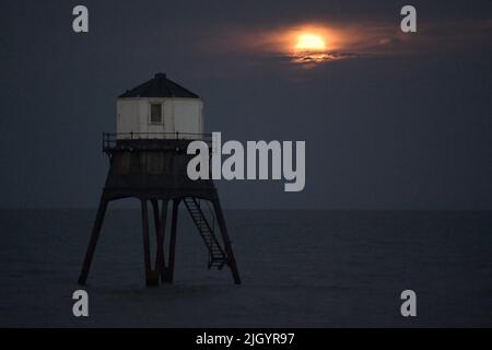 Essex, Großbritannien. 13.. Juli 2022. Dovercourt Essex UK 13.. Juli 22 der Super Buck Moon steigt hinter dem Dovercourt Lower Lighthouse in Essex auf. Der Super Buck Moon ist der zweite Supermond des Jahres und der erste Vollmond des Sommers 2022. Quelle: MARTIN DALTON/Alamy Live News Stockfoto