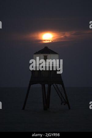 Essex, Großbritannien. 13.. Juli 2022. Dovercourt Essex UK 13.. Juli 22 der Super Buck Moon steigt hinter dem Dovercourt Lower Lighthouse in Essex auf. Der Super Buck Moon ist der zweite Supermond des Jahres und der erste Vollmond des Sommers 2022. Quelle: MARTIN DALTON/Alamy Live News Stockfoto