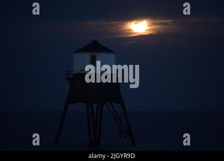 Essex, Großbritannien. 13.. Juli 2022. Dovercourt Essex UK 13.. Juli 22 der Super Buck Moon steigt hinter dem Dovercourt Lower Lighthouse in Essex auf. Der Super Buck Moon ist der zweite Supermond des Jahres und der erste Vollmond des Sommers 2022. Quelle: MARTIN DALTON/Alamy Live News Stockfoto