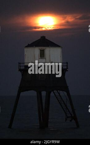 Essex, Großbritannien. 13.. Juli 2022. Dovercourt Essex UK 13.. Juli 22 der Super Buck Moon steigt hinter dem Dovercourt Lower Lighthouse in Essex auf. Der Super Buck Moon ist der zweite Supermond des Jahres und der erste Vollmond des Sommers 2022. Quelle: MARTIN DALTON/Alamy Live News Stockfoto