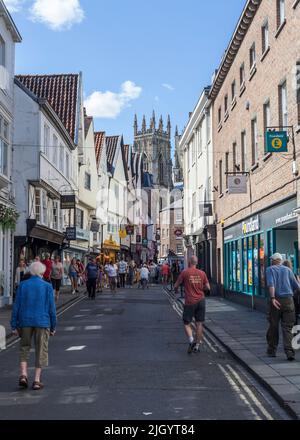 Eine Straßenszene in Low Petergate, York, North Yorkshire, England, Großbritannien mit dem York Minster im Hintergrund Stockfoto