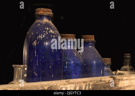 Eine Sammlung antiker Flaschen sitzt zusammen mit anderen Gegenständen im Fenster eines verlassenen Ladens. Stockfoto