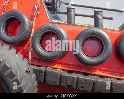 Schutz der Seite des Schiffes mit Autoreifen. Festfahrtes Schiff. Bullaugen im Laderaum. Schiff am Pier. Ausrüstung im Hafen. Bord des Schiffes Stockfoto