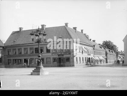 Stora Torget und Kungsängsgatan, Dragarbrunn, Uppsara von Nordwesten 1901 - 1902. Das sogenannte Lokkska-Apothekenhaus in Stora Torget wurde um 1770 vom Apotheker Christian Ludvig Lokk erbaut. LOKK engagierte Carl Wilhelm Scheele als Assistenten in seiner Apotheke, der Waffe von Upland. Im Jahr 1890s wurde der Name der Apotheke nach dem Namen der Nachbarschaft in „der Löwe“ geändert. Das Haus wurde 1960 abgerissen und durch das heutige Tempohaus ersetzt. Im Hintergrund ist unter anderem der Geerska-Hof zu sehen. 'Aus Ola Ehn & Gunnar Elfström, die Jahrhundertwende Uppsala in Dahlgrens Bildern. Natur Stockfoto