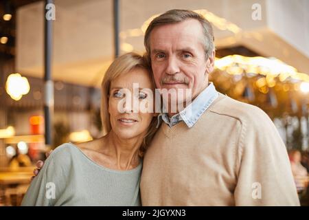Portrait eines lächelnden Naturpaares, das eine starke Ehe hat und sich im Café umarmt Stockfoto