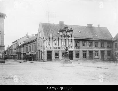 Billbergska House in Stora Torget, Uppshala 1901 - 1902. Stora Torget und Vaksalagatan im Osten. Das sogenannte Billbergska-Haus wurde nach dem Brand 1766 von Docens Mechanics Gabriel Billberg in Stein errichtet. Ein bekannter Besitzer der Farm im 19.. Jahrhundert war der Gewürzhändler G W Gillberg. Hier leitete er den profitablen Handel, der den Grundstein für den Gillberg Children's House Fund legte. Der Hof wurde 1906 abgerissen, um Platz für das Haus der Uplandsbanken zu lassen. 'Aus Ola Ehn & Gunnar Elfström, die Jahrhundertwende Uppsala in Dahlgrens Bildern. Natur und Kultur 1977. Stockfoto