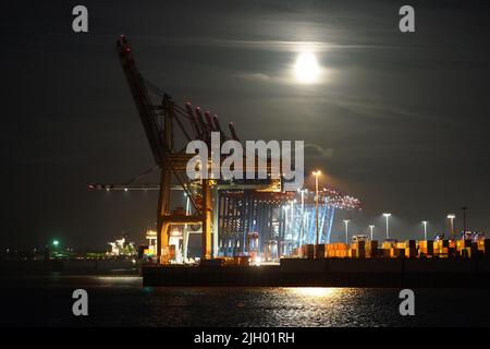 Hamburg, Deutschland. 13.. Juli 2022. Der Vollmond steigt am Abend über dem Hamburger Hafen auf. Gleichzeitig ist der Mond nahe an der Erde, weshalb er größer als gewöhnlich erscheint und als Supermond bezeichnet wird. Kredit: Marcus Brandt/dpa/Alamy Live Nachrichten Stockfoto