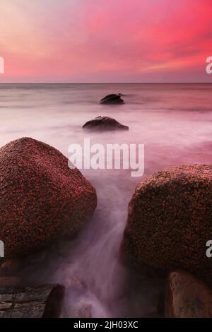 Sonnenuntergang über einem felsigen Strand in Australien Stockfoto