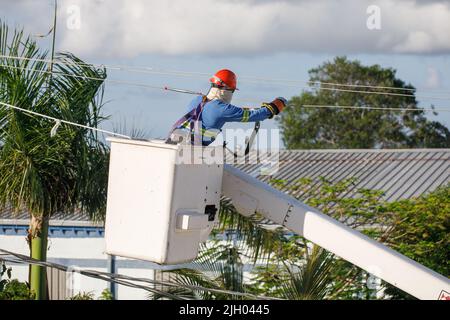 Ein Elektriker an einem Mast ist mit der Installation von elektrischen Drähten beschäftigt. Stockfoto