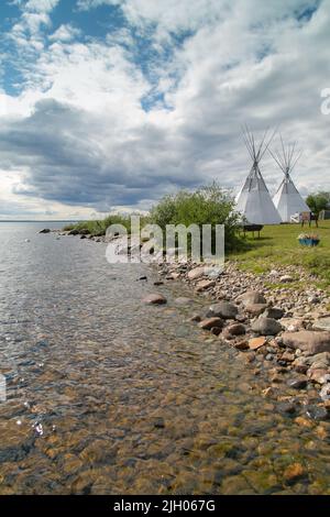 Küste des Great Bear Lake im Sommer, mit Tipis in der Ferne, in der nördlichen indigenen Gemeinde Deline, Northwest Territories, Kanada Stockfoto