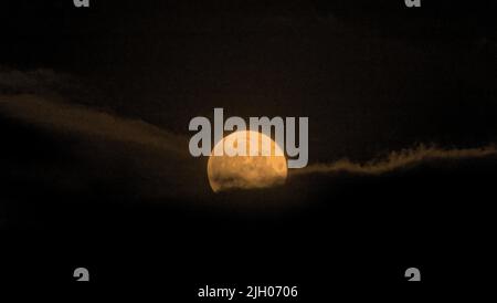 Glasgow, Schottland, Großbritannien, Juli 13. 2022. Wetter in Großbritannien: Super Buck Moon kämpft nach einem wechselhaften Tag, der regnete, durch einen bewölkten Himmel über den Lichtern des Südens der Stadt. Credit Gerard Ferry/Alamy Live News Stockfoto