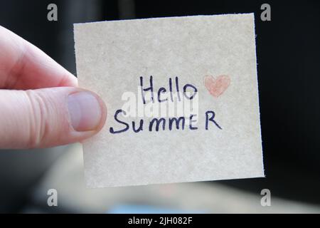 Hallo Sommer. Kreatives Konzept. Hand mit einem Anhänger mit der Aufschrift. Stockfoto