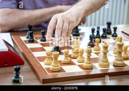 Berlin, Deutschland. 13.. Juli 2022. Eine Hand bewegt eine Figur während der Werner Ott Open des Kreuzberger Sommers im Berliner Kreuzberger Schachclub über das Schachbrett. Der Internationale Tag des Schachs wird am 20.07.2022 stattfinden. Quelle: Andreas Gora/dpa/Alamy Live News Stockfoto