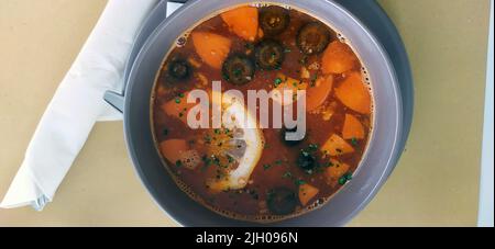 Typisch russisches Gericht heiße Gemüsesuppe mit Oliven und Karotten sowie Zitronenscheibe und Rote Beete Stockfoto