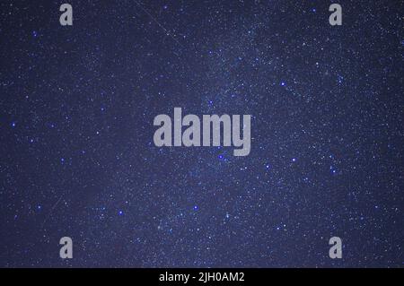 Ein Fragment des nächtlichen Sternenhimmels mit hellen Sternen und mehreren Spuren. Nächtlicher Sternenhimmel. Stockfoto