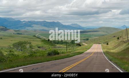 Die zweispurige Straße erstreckt sich in die weite Ferne in den Hügeln des westlichen Montana. Stockfoto