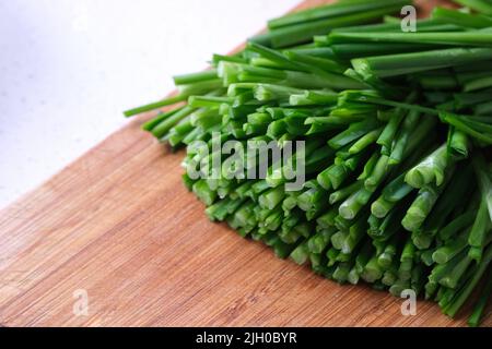 Gehackter grüner Knoblauch-Schnittlauch (chinesischer Schnittlauch) auf Holzschneidebrett Stockfoto