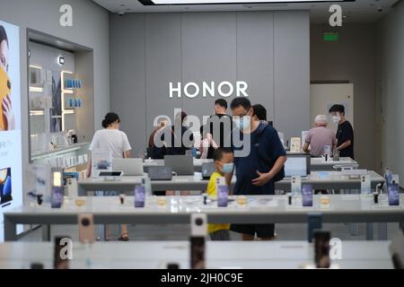 Shanghai, China-Juli 2. 2022: Chinesen in Gesichtsmaske, Einkaufen im Honor Smartphone-Einzelhandelsgeschäft. Honor ist eine chinesische Telefonmarke, die früher Eigentümer war Stockfoto