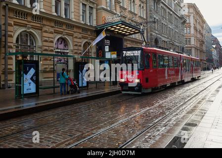 HELSINKI, FINNLAND - 16. SEPTEMBER 2017: Rote Straßenbahn kommt zu einer Haltestelle auf einer Stadtstraße Stockfoto