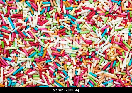 Textur von Süßigkeiten mehrfarbigen Streuseln. Regenbogenfarben bestreut Hintergrund. Stockfoto