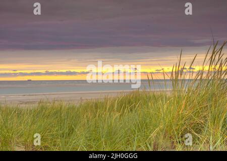 Ein schöner Sonnenuntergang in den Dünen von Langeoog an einem bewölkten Abend. Stockfoto