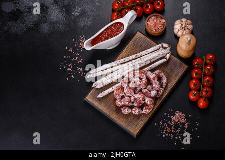 Spanische Fuet-Wurstscheiben, auf dunklem Betongrund Stockfoto