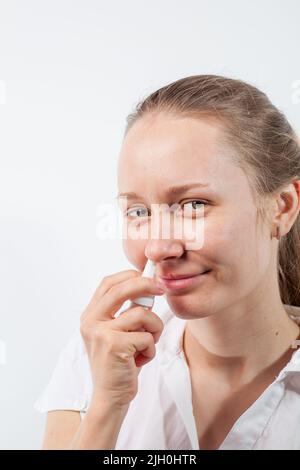 Das Mädchen tropft Nasentropfen aus einer laufenden Nase mit Influenza Stockfoto